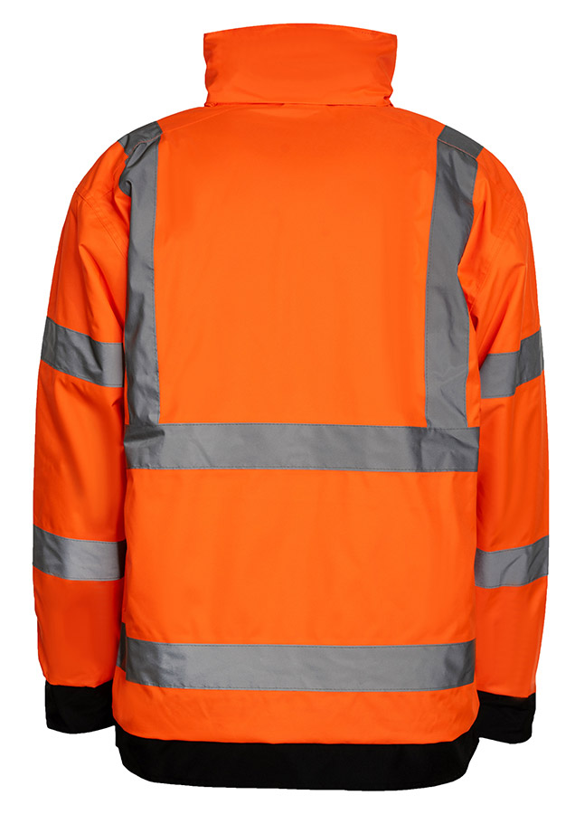 Erwachsener Bauarbeiter in gelber Korntex Hochsichtbarkeits-Regenjacke und gelbem Schutzhelm trägt eine Schaufel auf einer Baustelle.