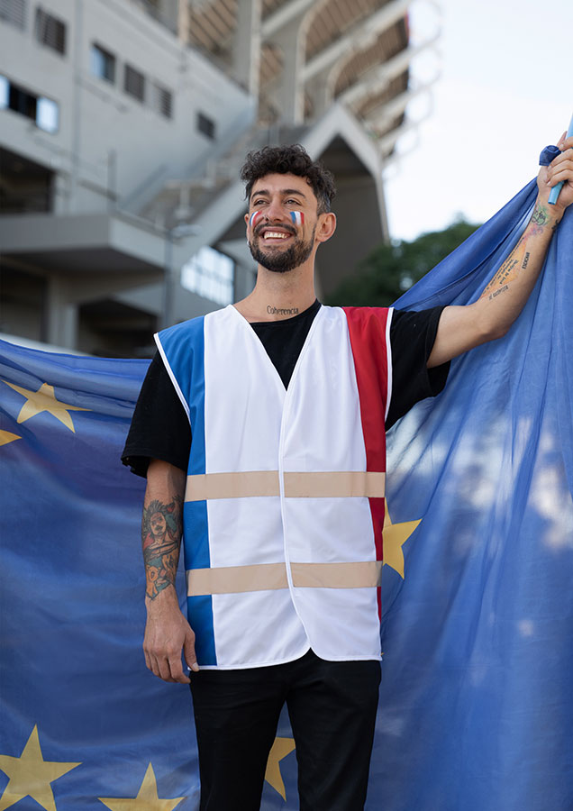 Französischer Erwachsener Fan in Korntex Nationen-Warnweste jubelt vor einem Stadion mit einer EU-Fahne