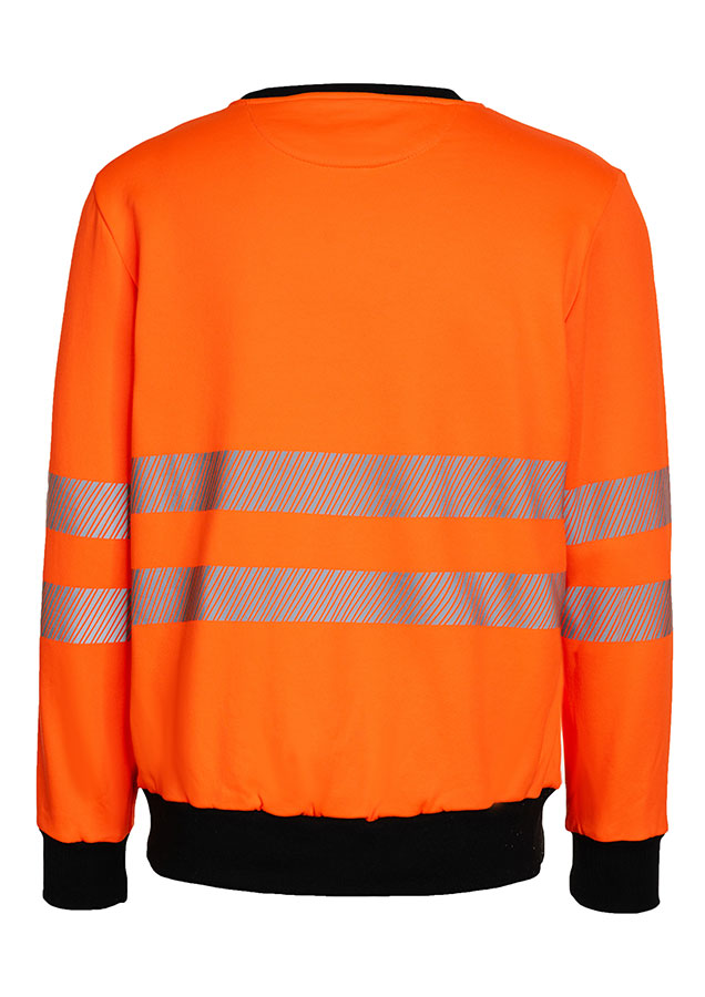 Erwachsener trägt ein gelbes Korntex-Sweatshirt mit schwarzer Brustpartie in einem industriellen Umfeld