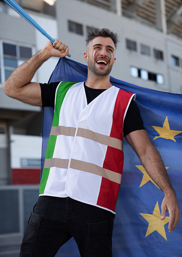 Freudestrahlender Erwachsener Mann in italienischer Korntex Nationen-Warnweste schwenkt eine Fahne vor einem Stadion