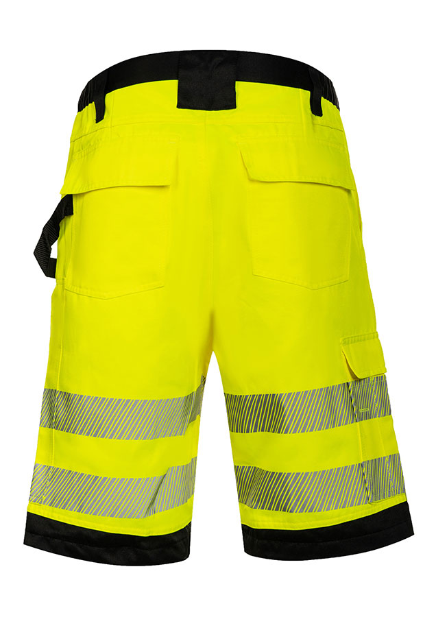 Erwachsener trägt unter anderem eine signalgelbe Korntex-Shorts mit schwarzen Partien in einem industriellen Umfeld