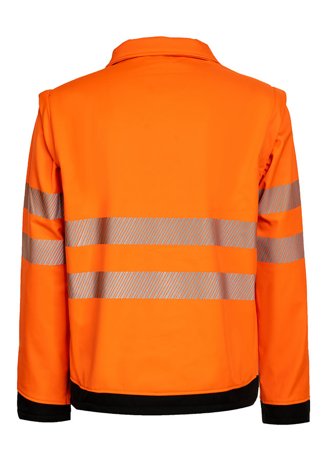 Erwachsener trägt eine gelbe Korntex-Softshell-Jacke mit schwarzer Brustpartie in einem industriellen Umfeld