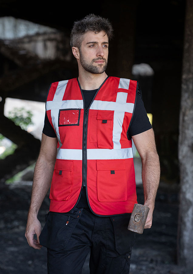 Vuxen i röd, fodrad Korntex-varningsväst med dragkedja i en industriell miljö