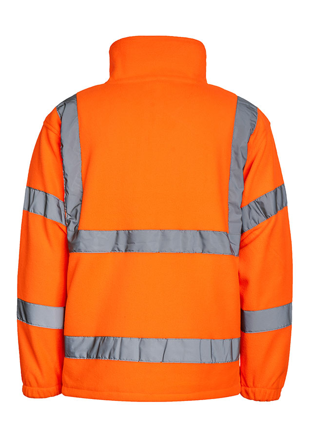 Erwachsener Mann läuft in signal-oranger Korntex Warnschutz-Fleecejacke mit Reflexstreifen vor einem Industriegebäude entlang.