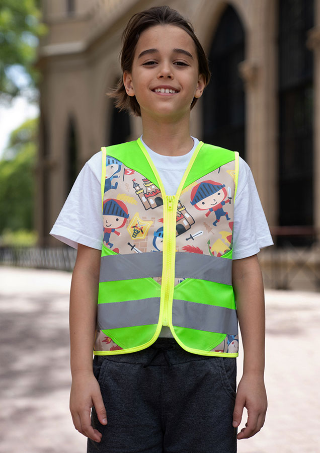Kind in einer neongrünen Korntex-Warnweste mit Ritter-Muster in einem Park