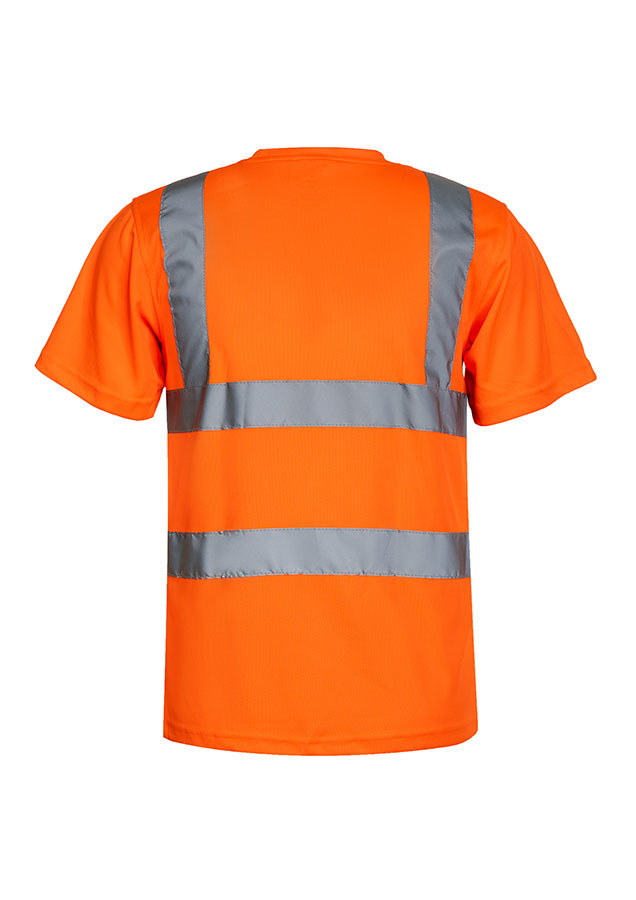 Erwachsene Frau steht in signal-orangenem Korntex Warnschutz-T-Shirt und weißem Schutzhelm vor einem Gerüst auf einer Industriebaustelle