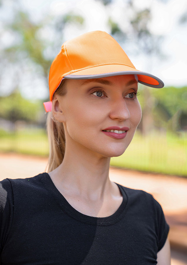 Porträt einer Erwachsenen lächelnden Frau mit reflektierender orangener Korntex Kappe im Park